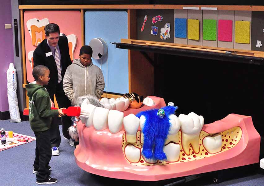 Students brushing and flossing Mr. Big Mouth at the Poe Center.