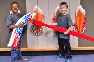 Two students posing with giant toothbrush and toothpaste.