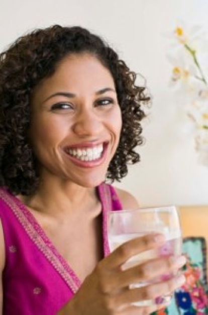 african american woman holds glass of water and smiles