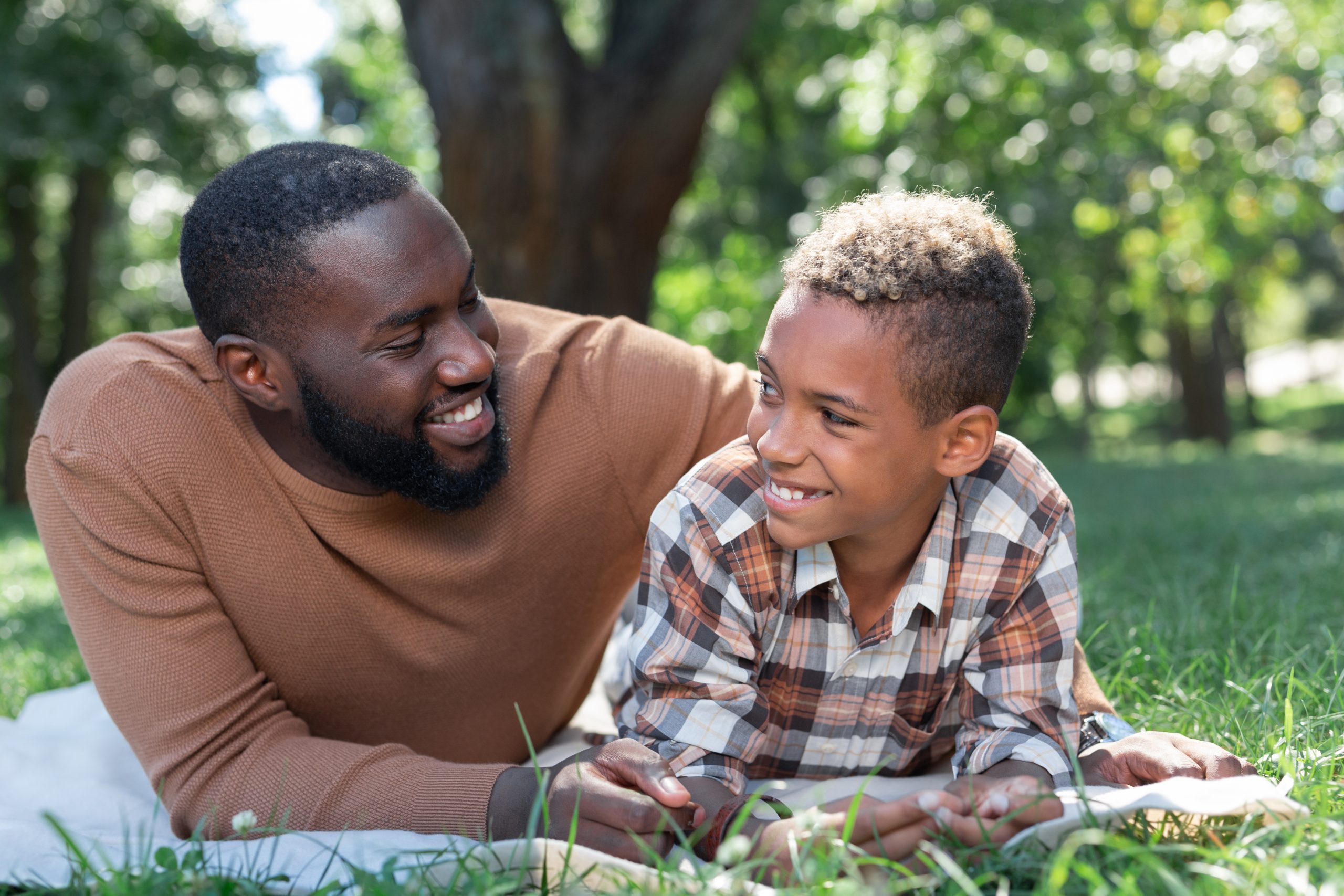 Father and son smiling while relaxing outside.