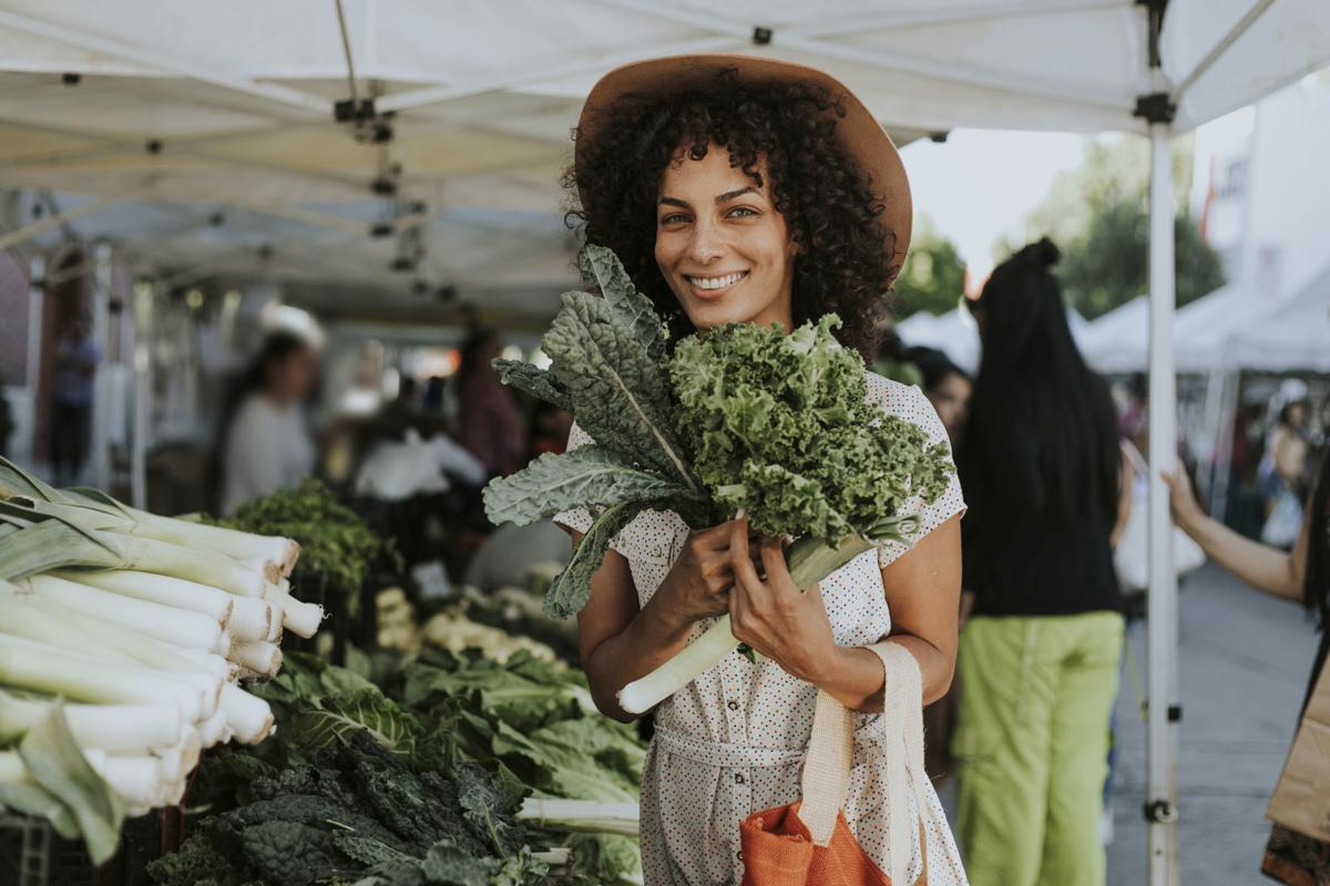 lady in hat holding greens at farmers market