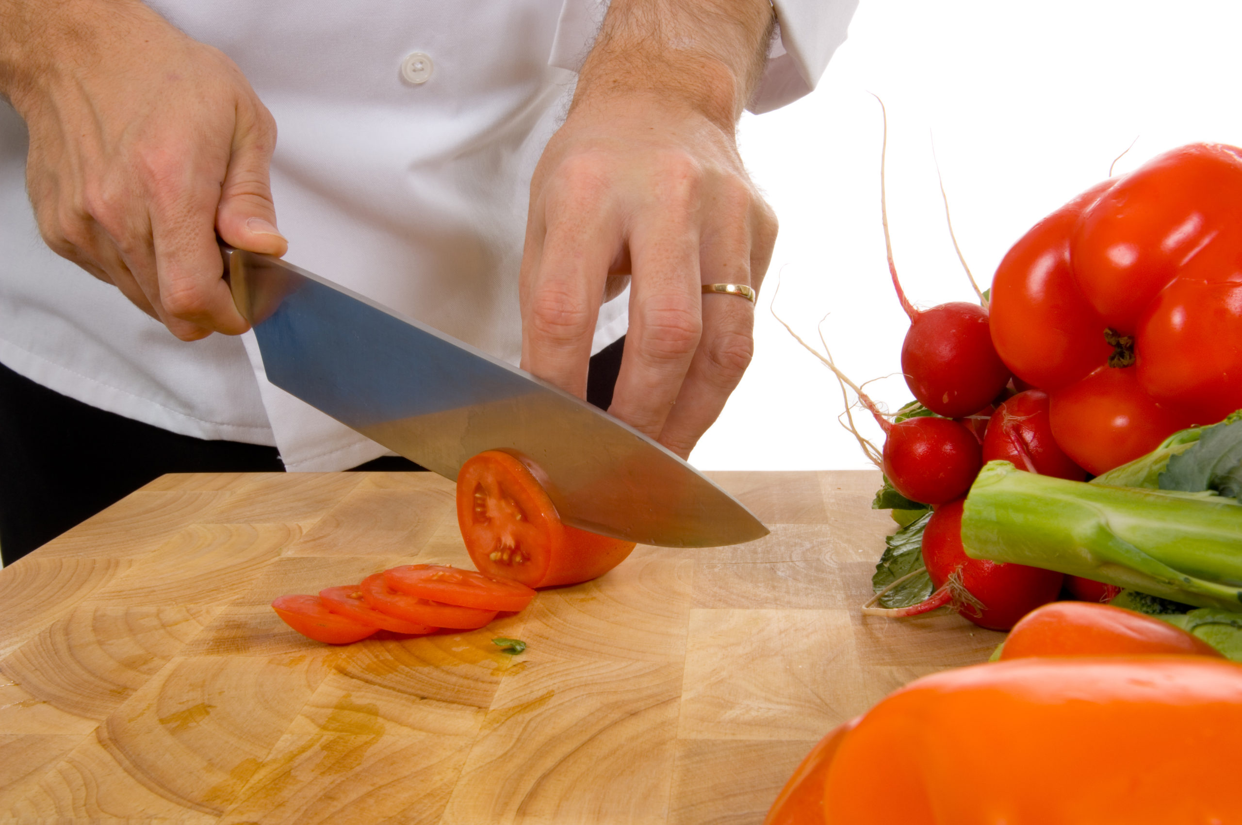 Professional chef slicing roma tomato on white background