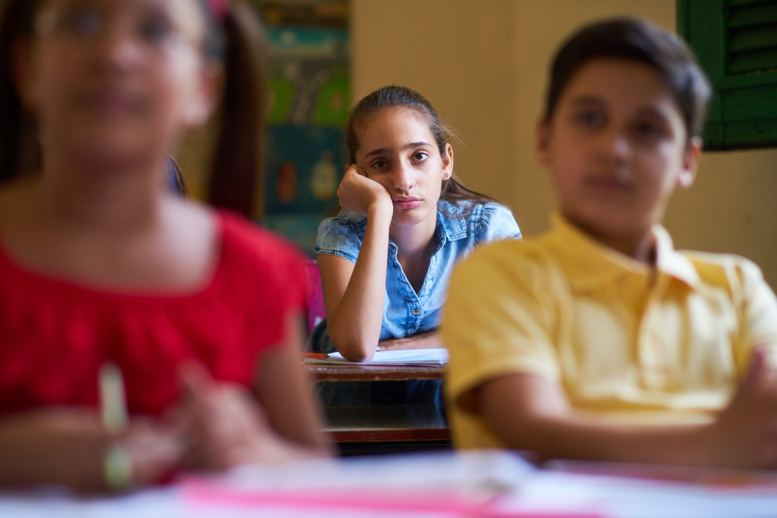 Young people and education. Group of hispanic students in class at school during lesson. Girl with anxiety, bored female student