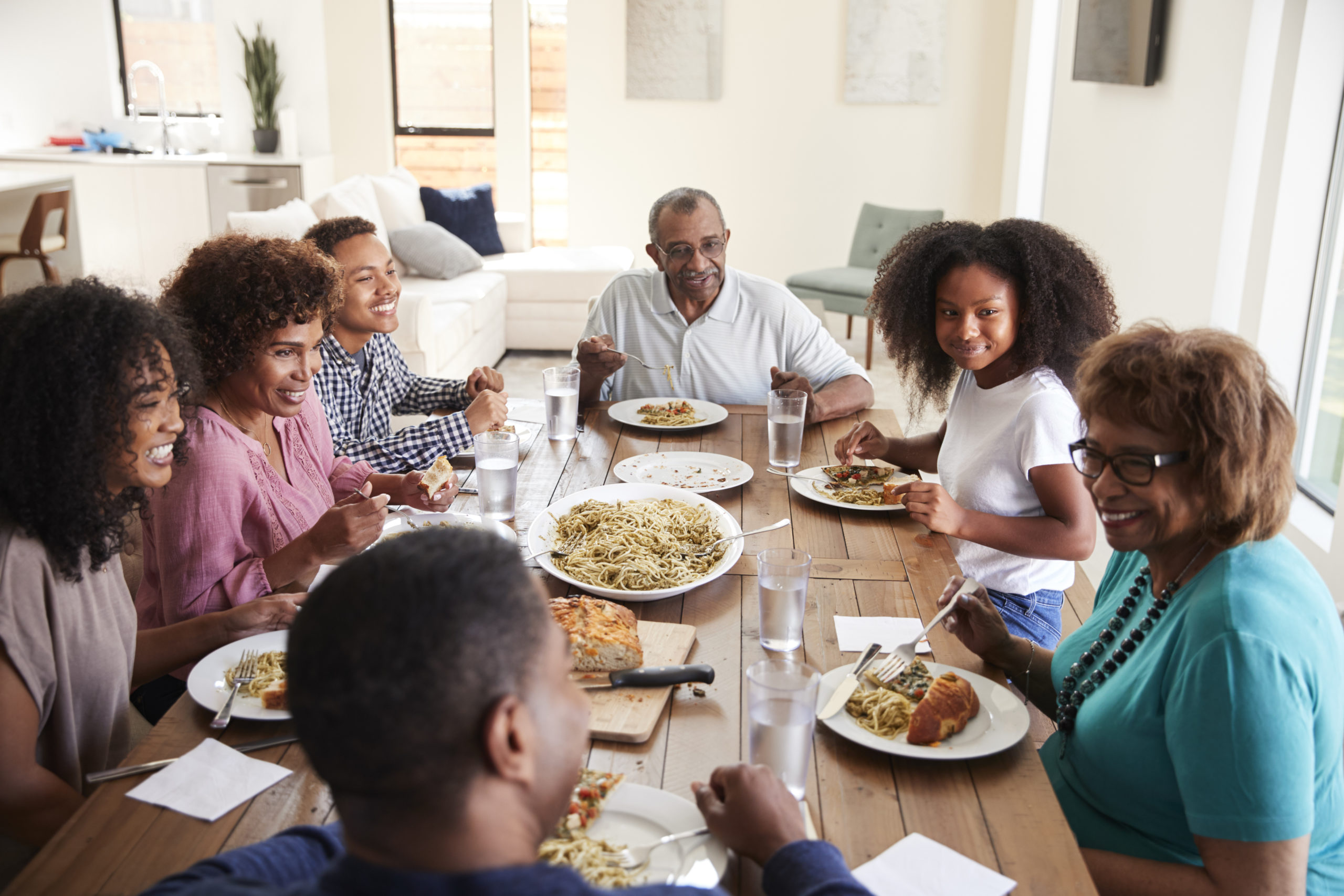 Three generation black family sitting at the table talking and eating dinner together, close up