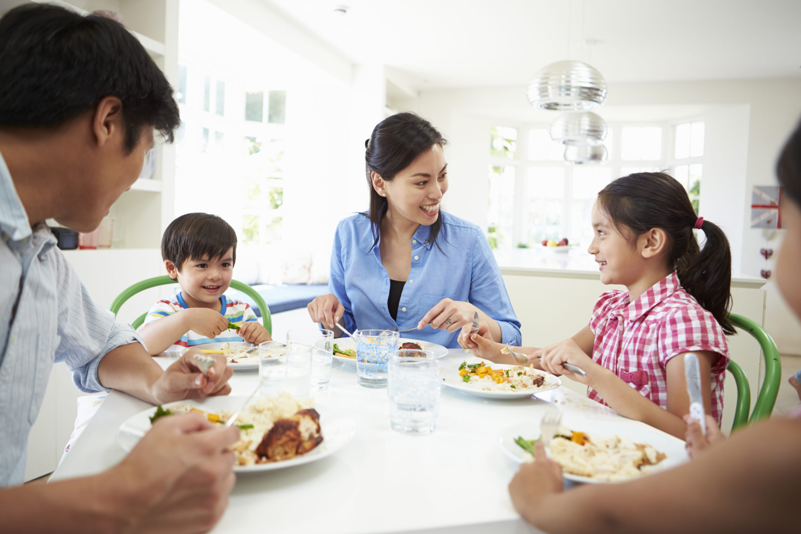 Asian Family Sitting At Table Eating Meal Together