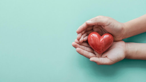 Hands holding a heart shape on a teal background