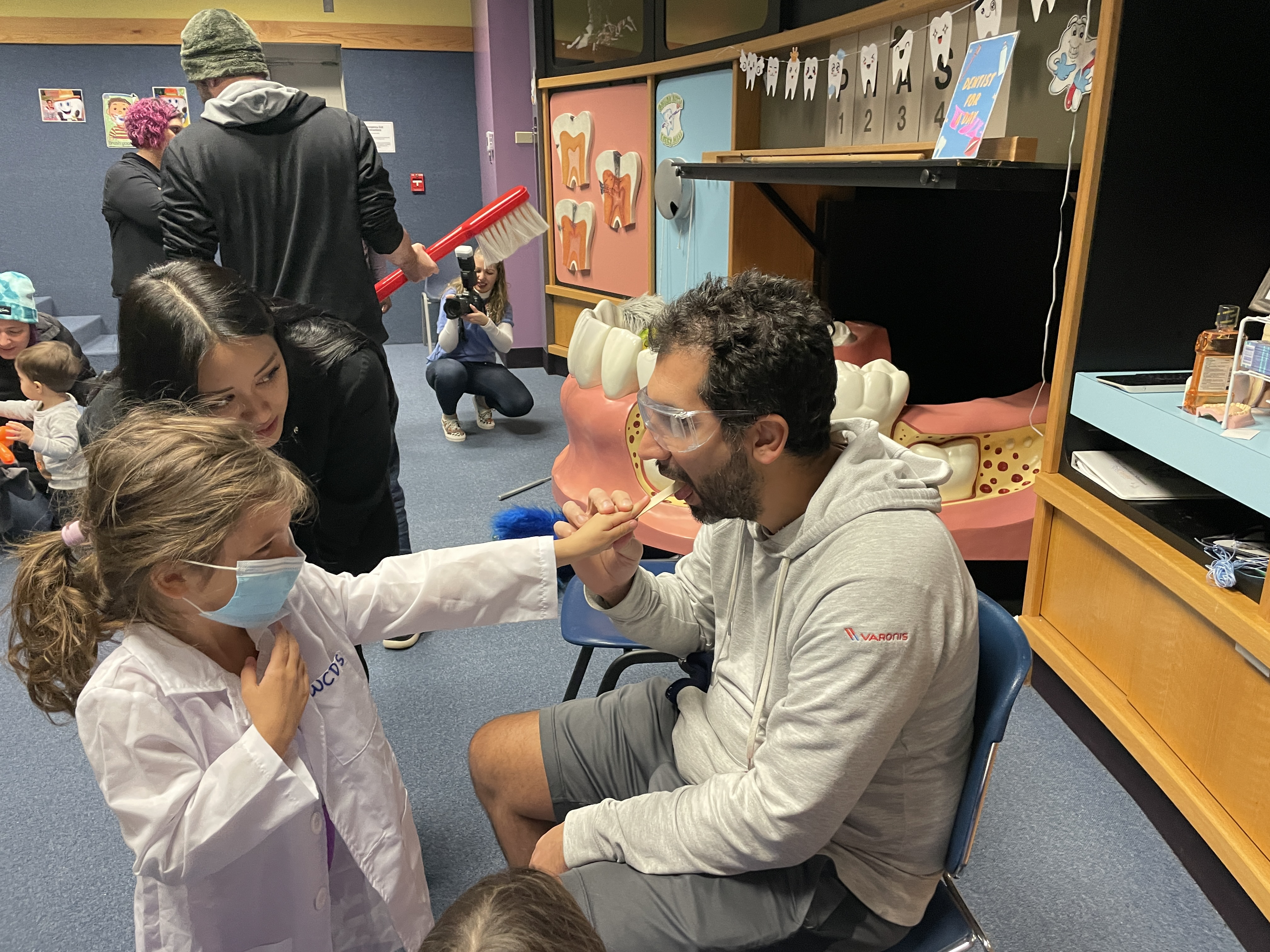 A child and their parent wearing lab coats pretending to do an exam for educational purposes.