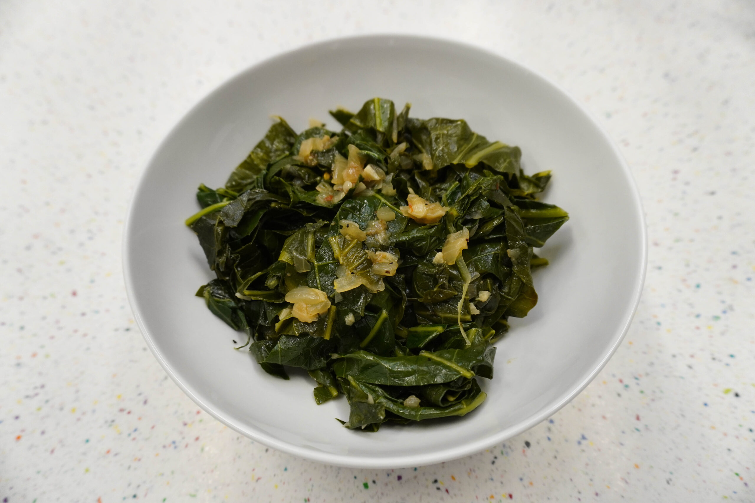 cooked collard greens in a white bowl.