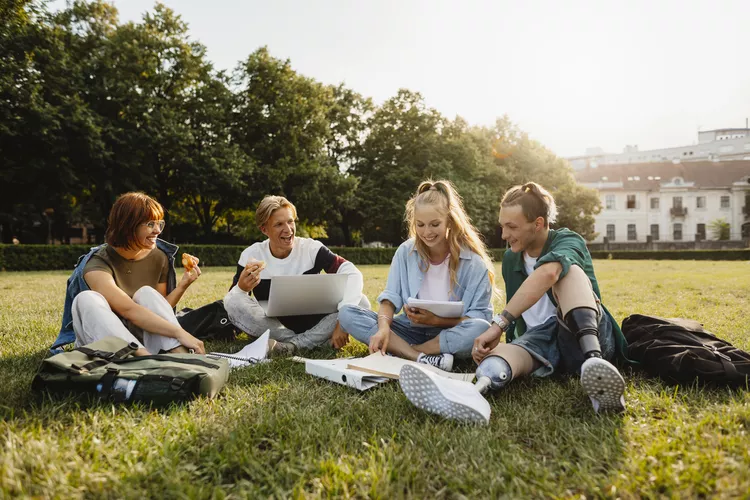 Four students sitting on the grass studying.