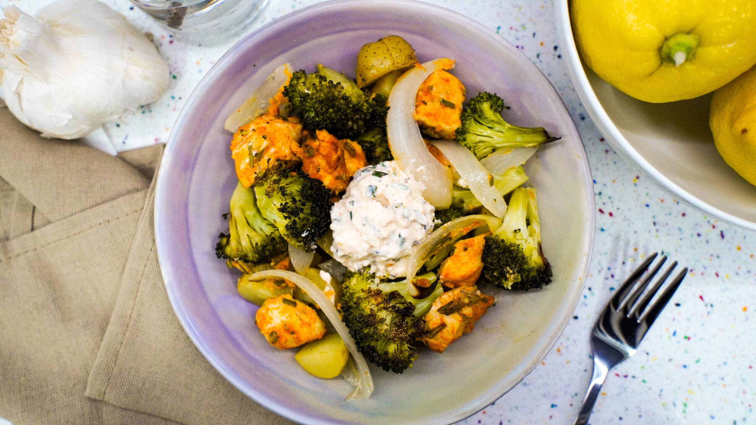 Broccoli, chicken, and onion on a plate with the yogurt dip on top.