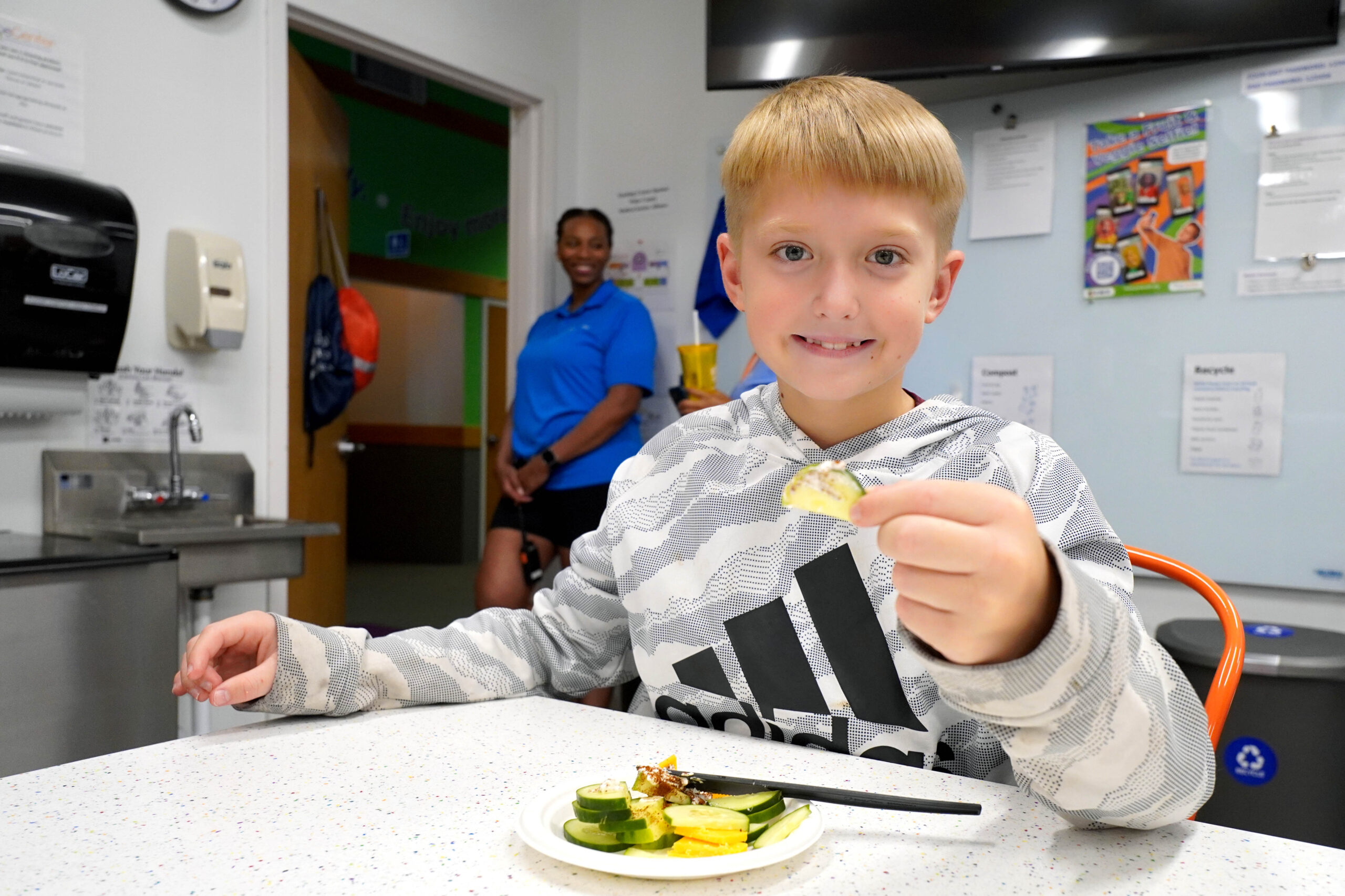 A happy camper samples delicious and healthy veggies in the Poe Center CookWELL Kitchen during Healthy Habits Camp 2025.