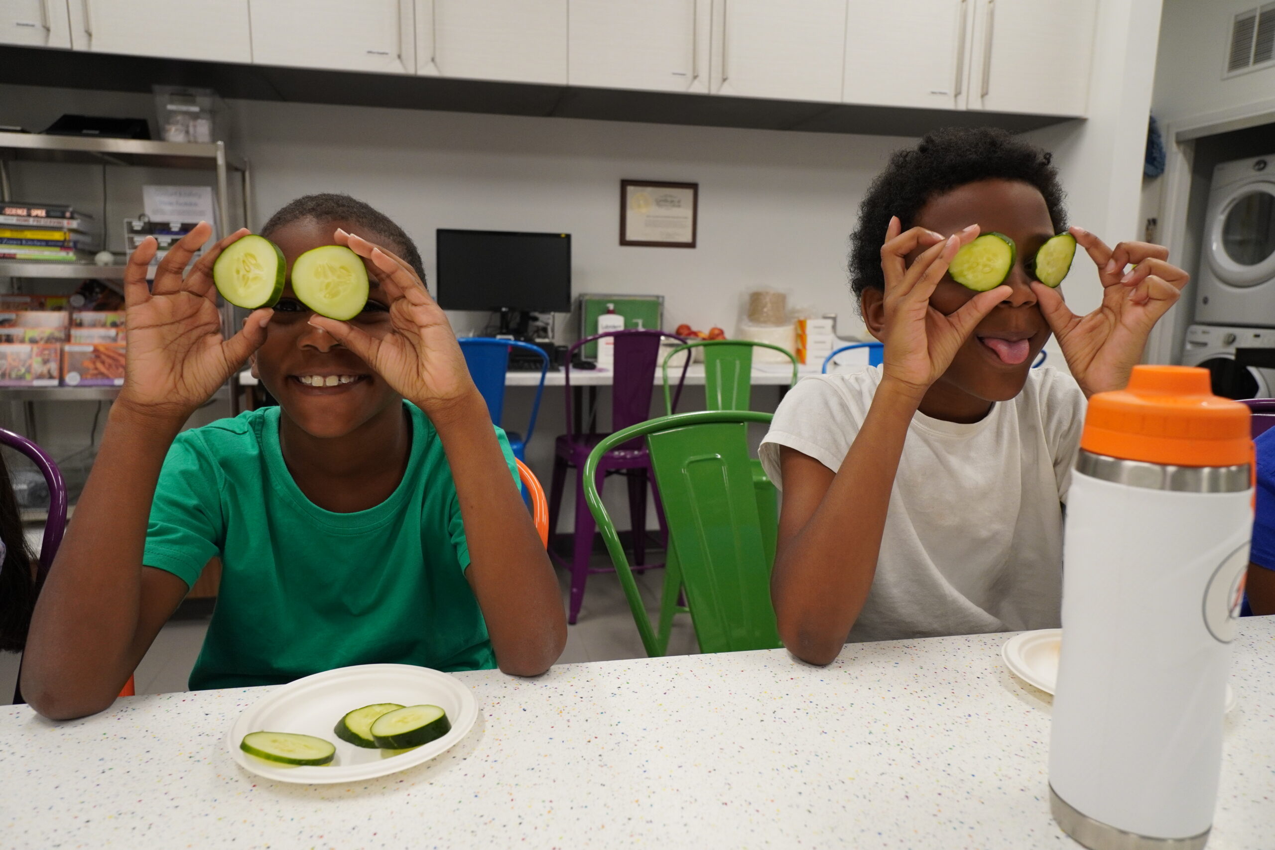 Two happy campers hold cucumbers over their eyes during Healthy Habits Camp at the Poe Center.