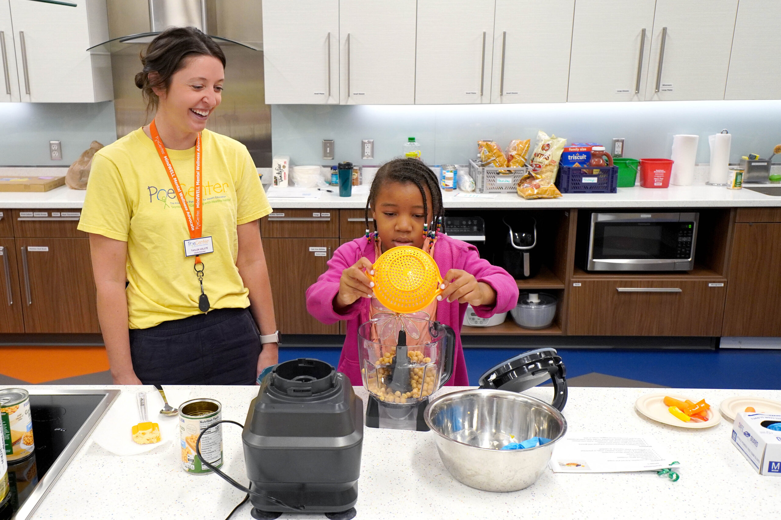 A camper measures food with the help of a camp counselor at the Poe Center CookWELL Kitchen at the Poe Center during Healthy Habits Camp 2025.