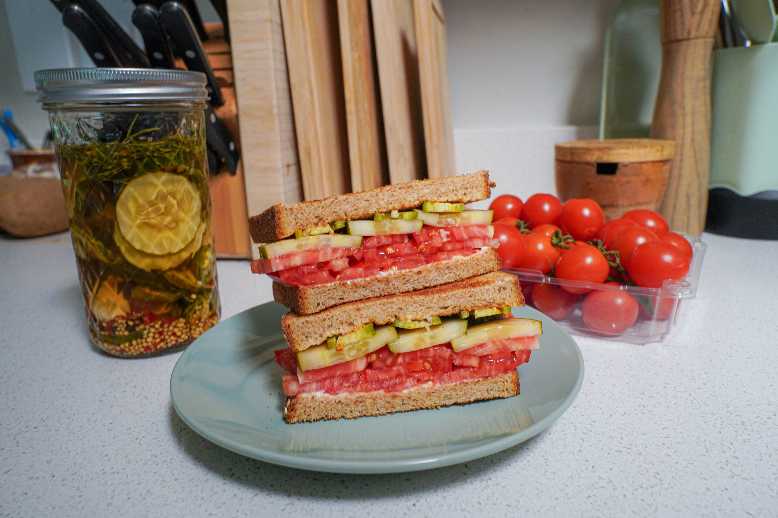 Pickle and cucumber sandwich with the pickle jar in the background.