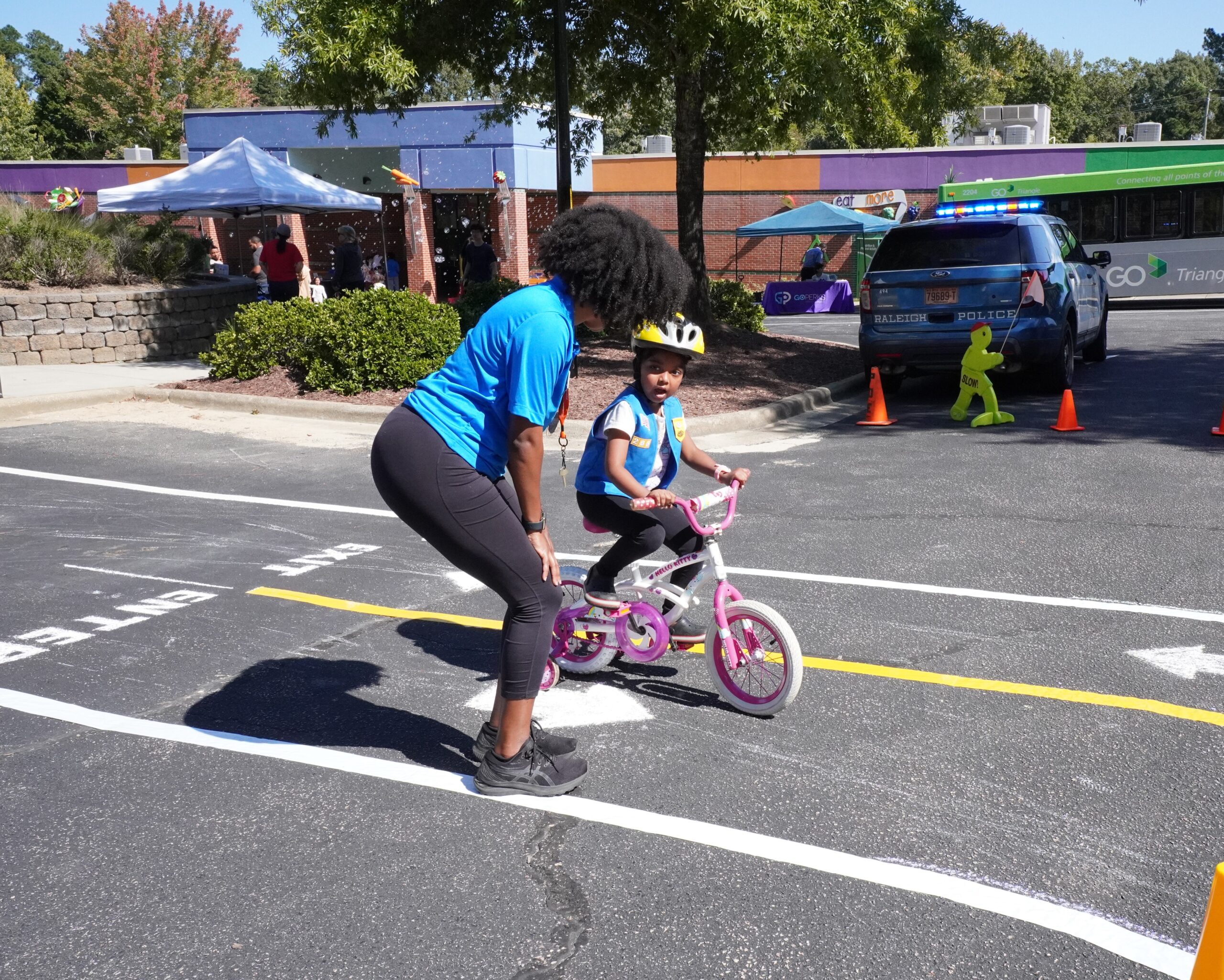 A Poe Center volunteer helps a young child navigate the bike traffic safety course