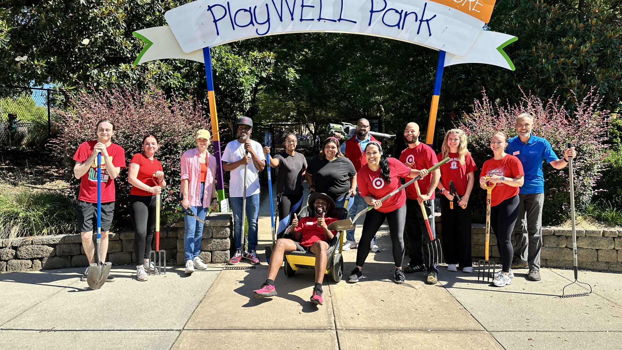 Poe Center volunteers stand in front of the PlayWELL Park sign