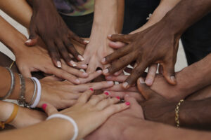 a group of hands placed on top of each other making a circle and representing the diversity of humans