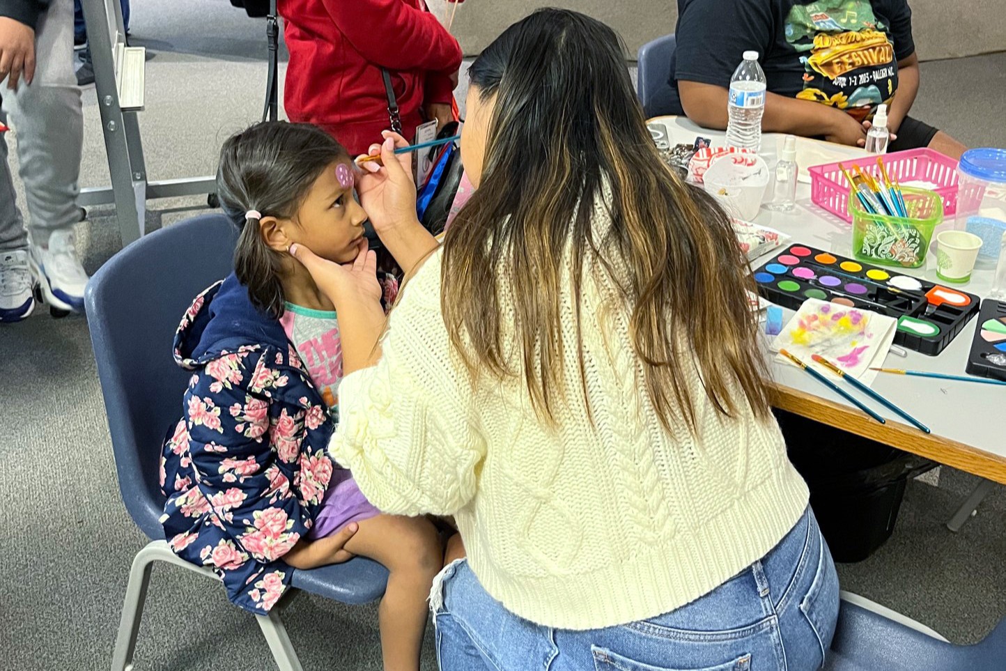 Young participants of the Summer Meals program at the Poe Center smile at the camera as they eat nutritious lunches outside on a picnic table.